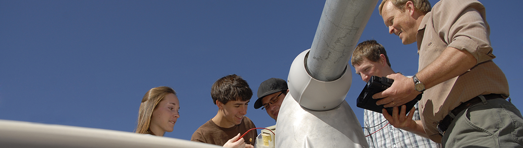 Students and teacher examine building data under blue skies