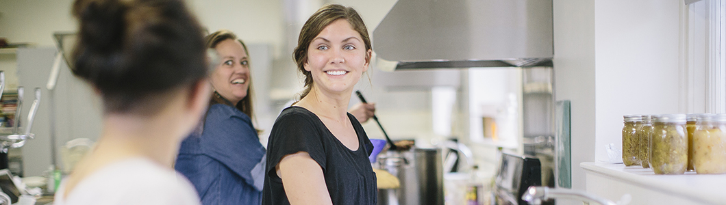 A young woman smiles in an industrial kitchen.