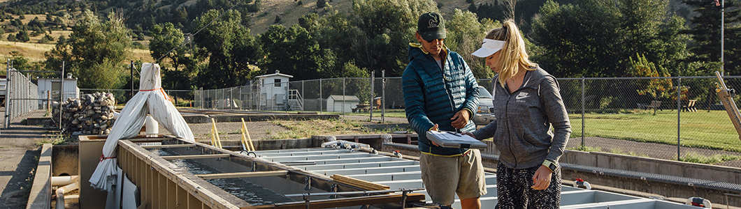 A man and a woman inspect a series of pools at a fishery.