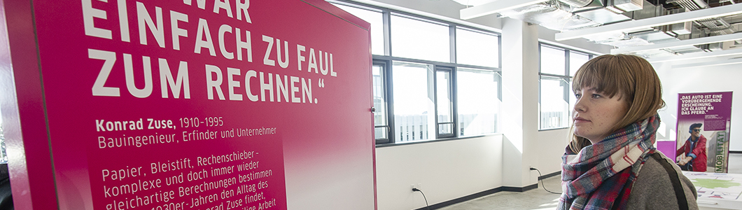 A young woman reads an exhibit sign written in German.