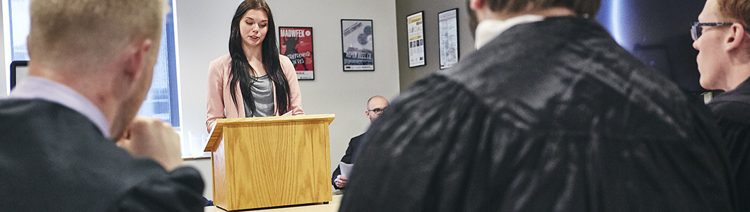 A young woman delivers a speech in front of a mock court.