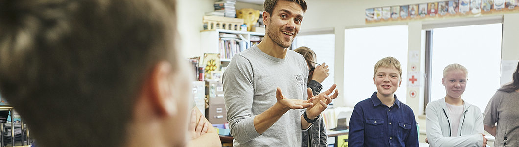 A young man talks in the center of a group of students.