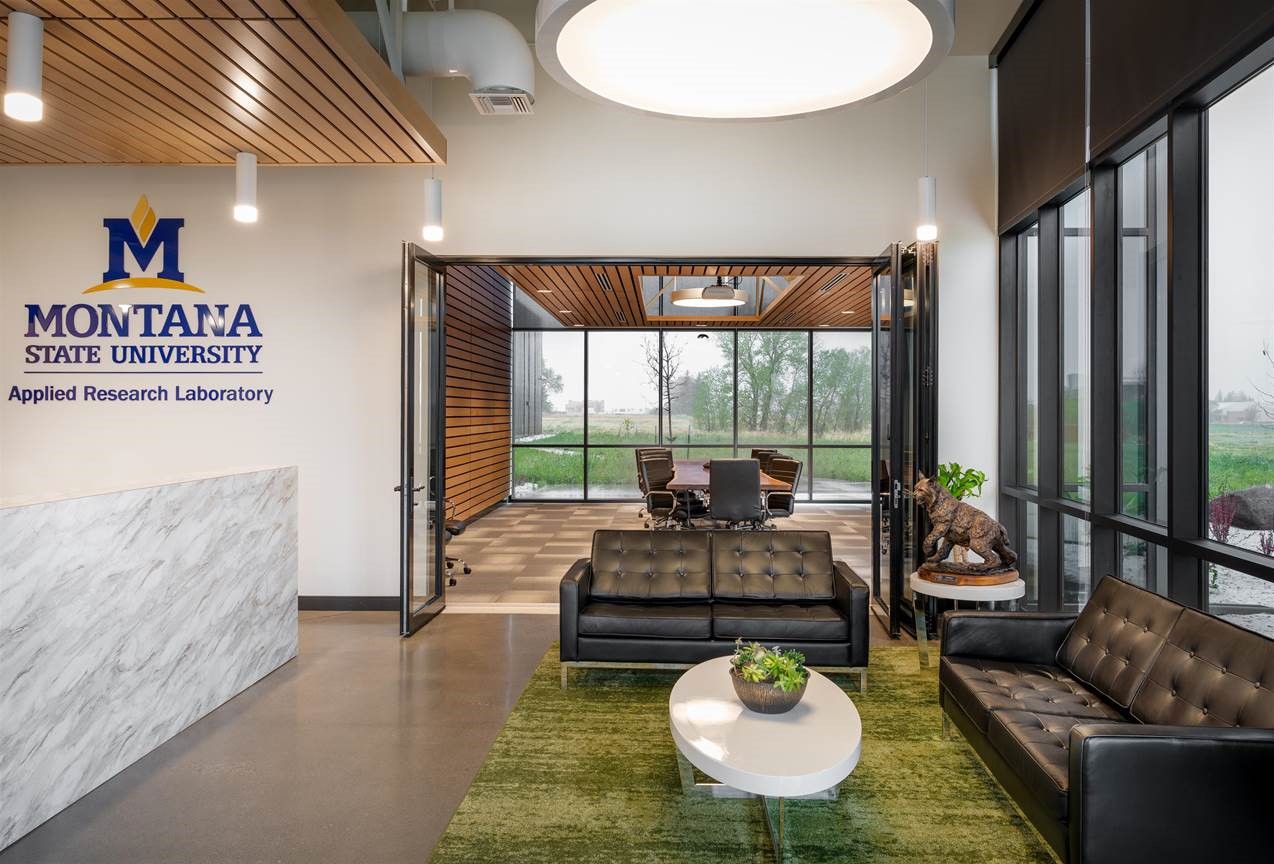 Building lobby, with two couches and a coffee table. A small Spirit bobcat statue sits in the corner, a conference room is in the distance. 