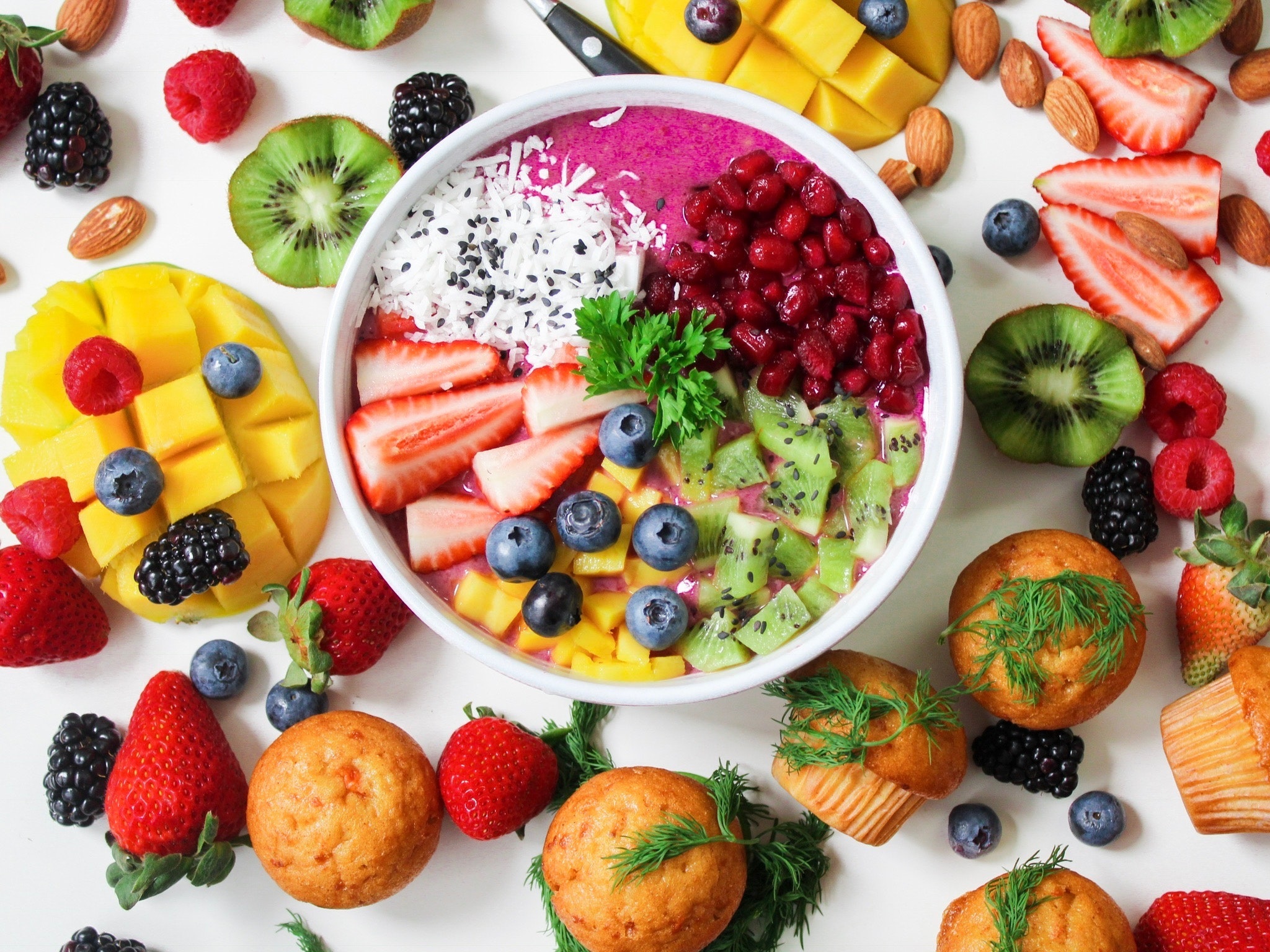 White table filled with a variety of fruits and muffins