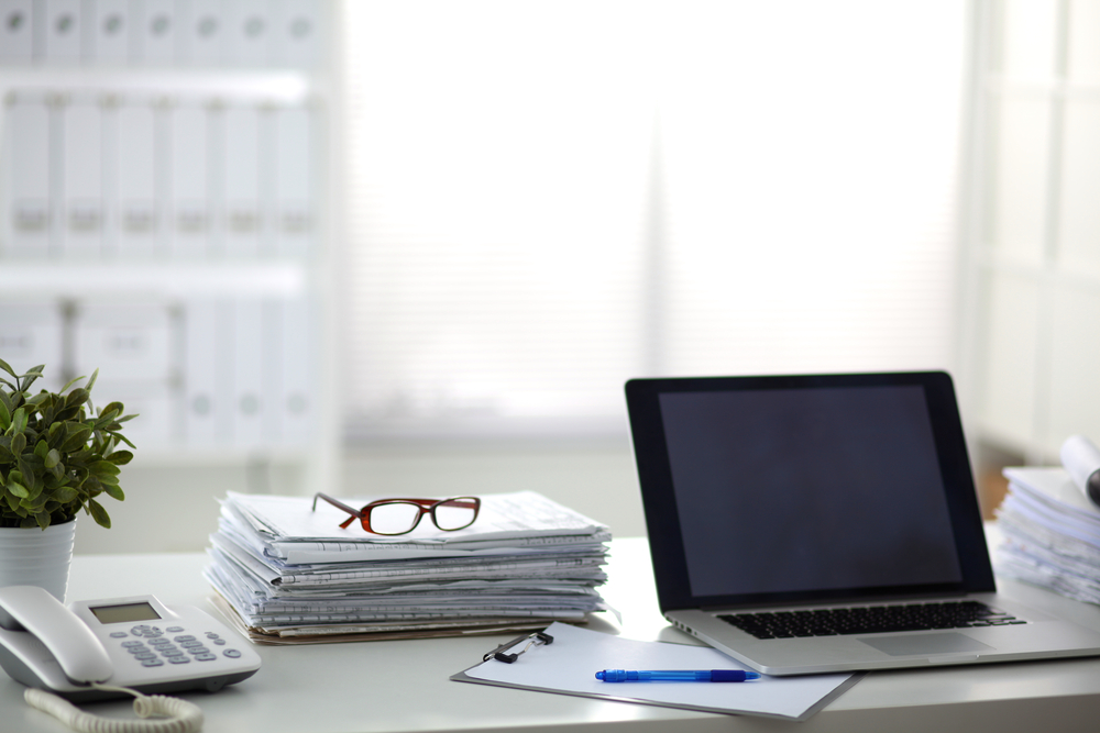 A computer on a desk with files. 