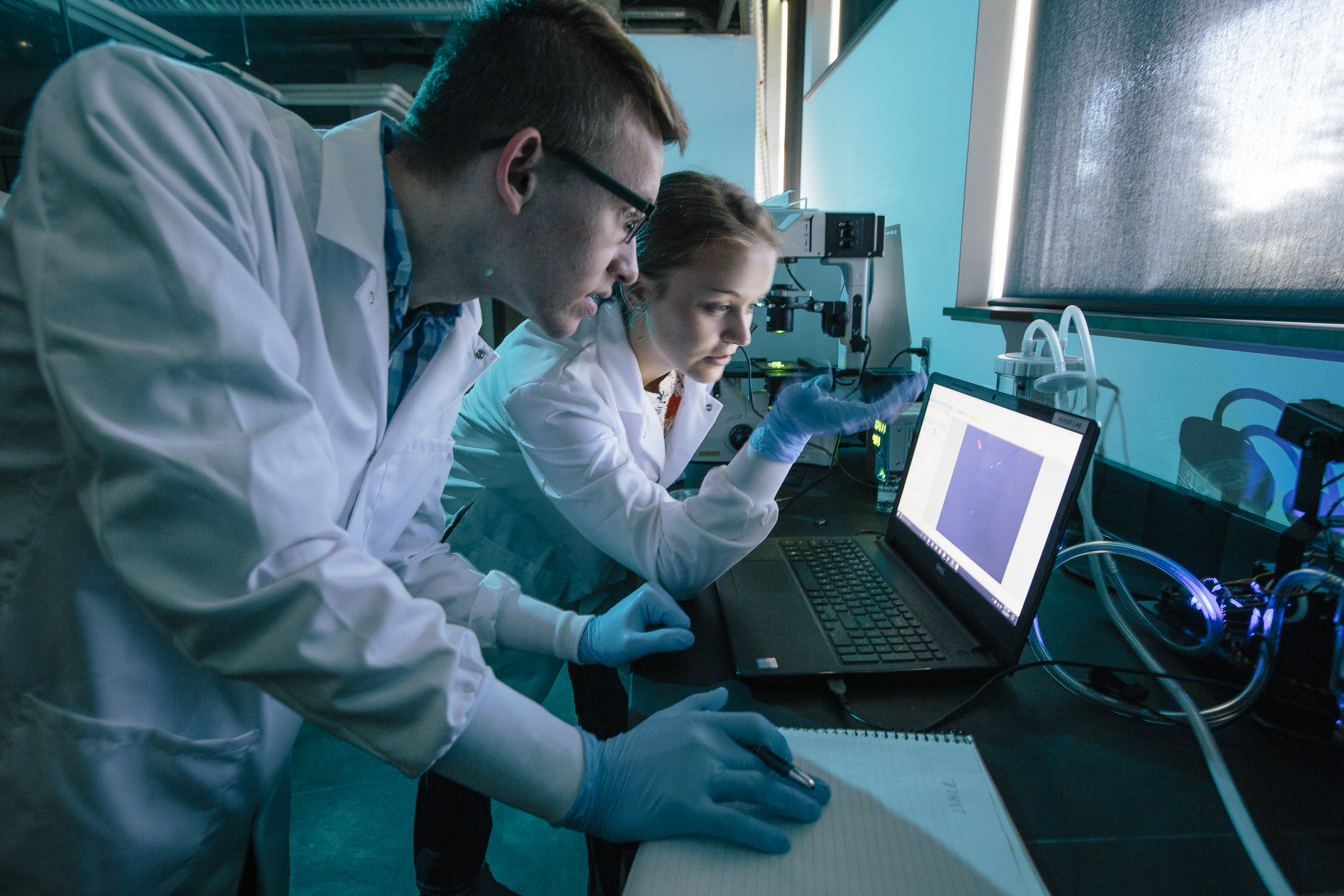 Two students in a lab reviewing data on a laptop